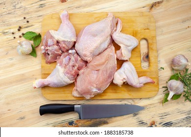 Different parts of raw chicken on wooden background