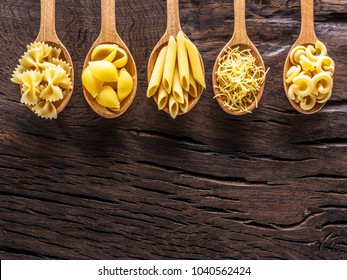 Different pasta types in wooden spoons on the table. Top view. - Powered by Shutterstock