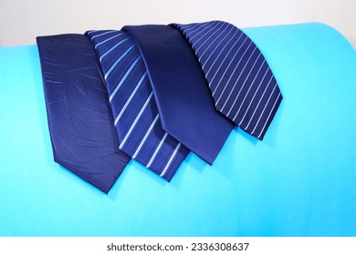 different patterns of neckties layered side by side with blue background, group of neck ties layered together close up shot noperson 