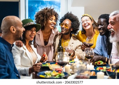 Different people of age and ethnicity eating a vegan dinner. Multiethnic group of friends having fun while sharing a meal in a warm and welcoming house.