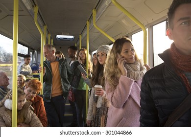 Different people can be seen traveling on the bus. Some are talking to other people, others are using technology or looking out the window.  