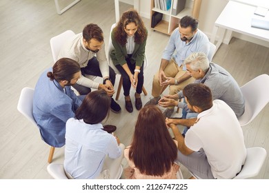 Different People Meeting In Group Therapy Session. Sad Unhappy Male And Female Patients Sitting In Circle, Talking And Discussing Their Mental Problems And Issues. High Angle Shot, View From Above