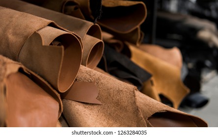 Different pieces of leather in a rolls. The pieces of the colored leathers. Rolls of natural brown red leather. Raw materials for manufacture of bags, shoes, clothing and accessories.