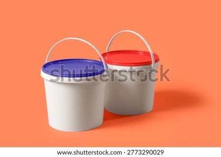 Different plastic paint buckets on orange background
