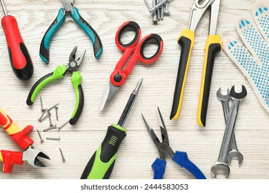 Different pliers, scissors and other tools for repair on wooden table, flat lay