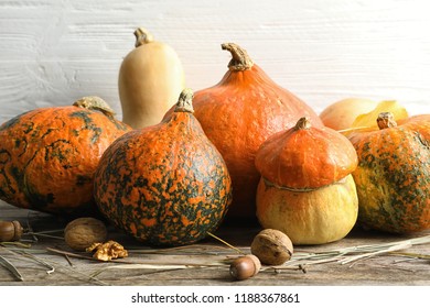 Different pumpkins on table against wooden wall. Autumn holidays