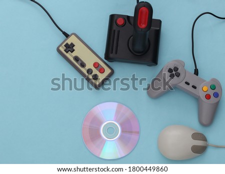 Different retro gamepads and joysticks, pc mouse, cd's on blue background. Video game.  Flat lay, top view