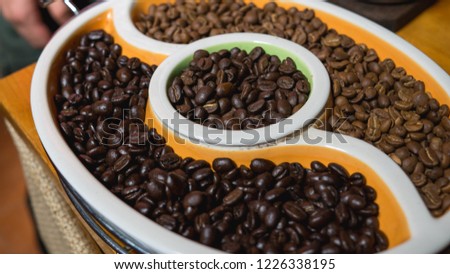 Different roasts of coffee beans - from light to espresso - in a procelain bowl
