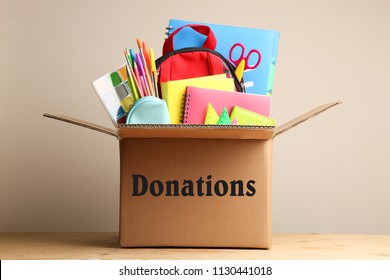 Different School Supplies In A Cardboard Box On A Neutral Background. Concept Donations.