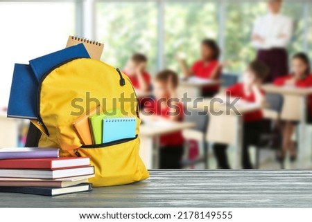 Different school supplies on wooden table in classroom