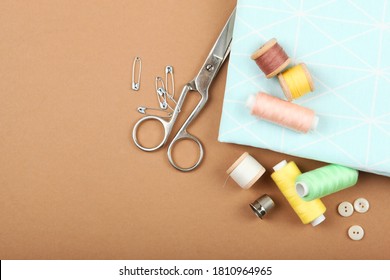different sewing accessories on the table. Threads, needles, pins, fabric and sewing scissors close up
