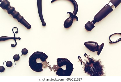 Different sex toys (dildo, fur handcuffs, love balls, butt plug, wand massager and other) are on a light background. Idea for sex shop advertising