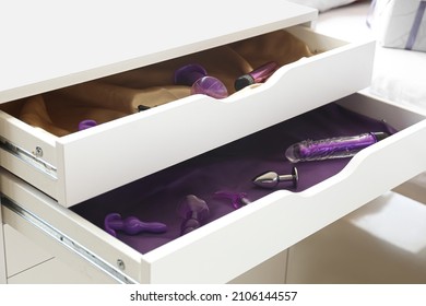 Different sex toys in open chest of drawers