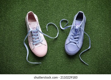 Different Shoes With Untied Laces On Color Background