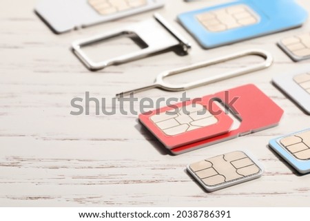 Different SIM cards, ejector and tray on white wooden background, closeup
