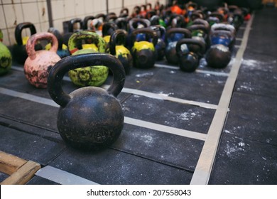 Different Sizes Of Kettlebells Weights Lying On Gym Floor. Equipment Commonly Used For Crossfit Training At Fitness Club