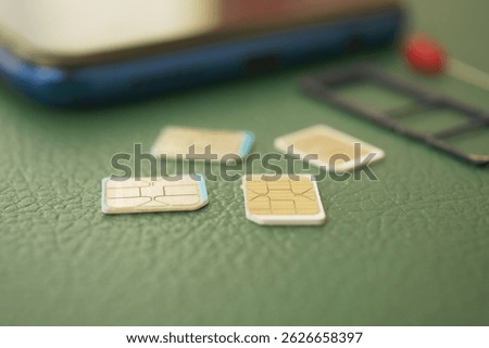 Different sizes of SIM cards next to a smartphone on green background