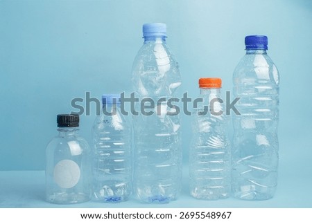 Different sizes of used plastic bottles lined up on a blue background, representing recycling, waste sorting, and environmental awareness.