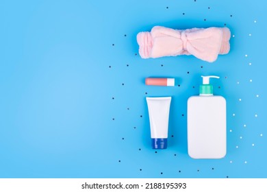 Different Skin Care Cosmetic Products With Headband For Spa On Blue Background, Top View, Flatlay
