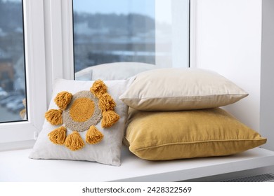 Different soft pillows on window sill indoors