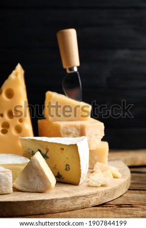 Different sorts of cheese and knife on wooden table against black background, closeup ストックフォト © 