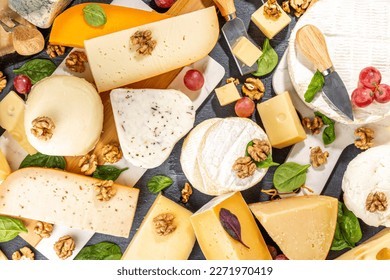 Different sorts of cheese set. Cheese platter with various cheese, with grapes, nuts, cheese knife and spices, black tiled background copy space - Powered by Shutterstock