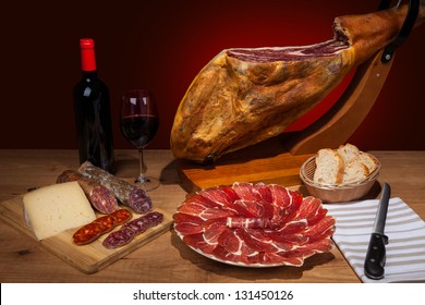 Different spanish embutidos on a table: jamon, chorizo, salami, cheese and a bottle of wine - Powered by Shutterstock