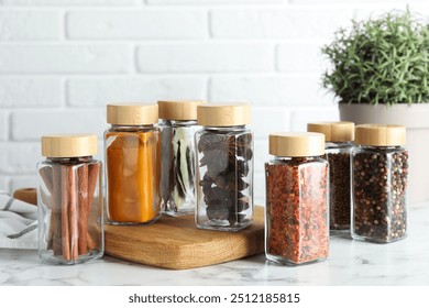 Different spices in glass jars on white marble table - Powered by Shutterstock