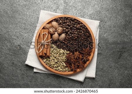 Different spices and nuts on gray textured table, top view