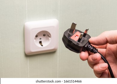 Different standards for electrical outlets. Unsuitable connector and plug in the hand of a person. Incompatibility, concept