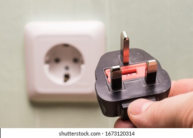 Different standards for electrical outlets. Unsuitable connector and plug in the hand of a person. Incompatibility, concept