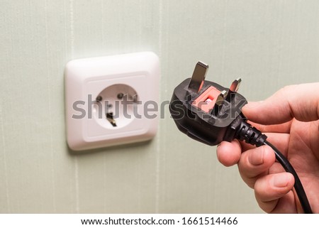 Different standards for electrical outlets. Unsuitable connector and plug in the hand of a person. Incompatibility, concept
