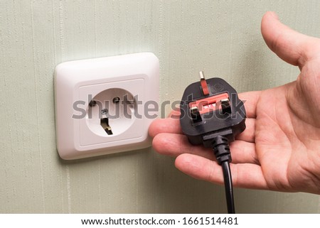 Different standards for electrical outlets. Unsuitable connector and plug in the hand of a person. Incompatibility, concept