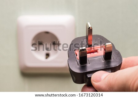 Different standards for electrical outlets. Unsuitable connector and plug in the hand of a person. Incompatibility, concept

