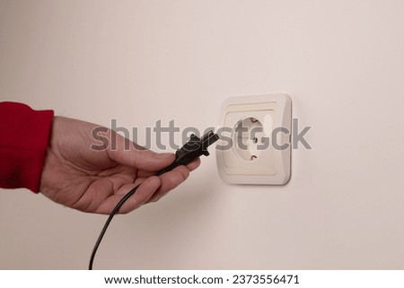 Different standards for electrical outlets. Unsuitable connector and plug in the hand of a person. Incompatibility, concept