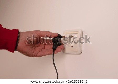 Different standards for electrical outlets. Unsuitable connector and plug in the hand of a person. Incompatibility, concept