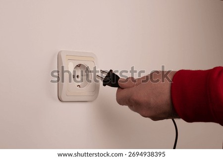 Different standards for electrical outlets. Unsuitable connector and plug in the hand of a person. Incompatibility, concept