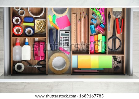 Different stationery in open desk drawer, top view