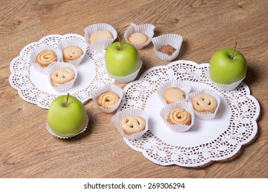 different sugar cookies and green apples on wooden table