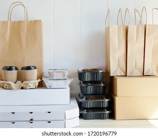 Different Takeout Containers, Packages And Carton Cups On Table Against White Wall. Online Food Delivery Service Concept