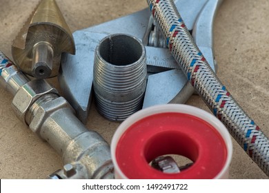 Different Things For Plumbers Lie On Ground. Teflon Tape, Wrench, Hose, Tube, Water Tap .