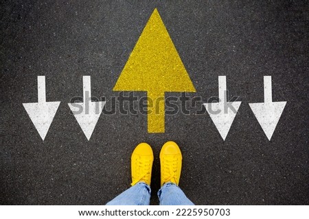 Different thinking and Business and technology disruption concept. Yellow big arrow opposite direction with white arrow on road asphalt. Standing out from the crowd