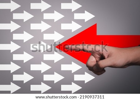 Different thinking concept. Business and study idea thinking poopsite disruption. Hand with big red arrow opposite direction with white arrow on gray background.