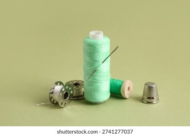 Different thread spools and thimble on green background, closeup