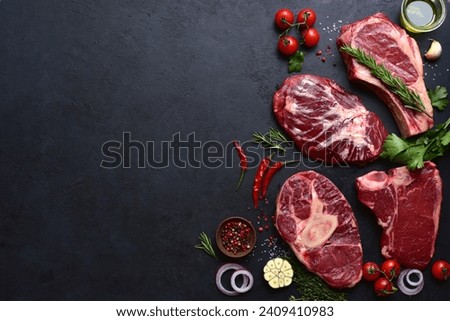 Different tipes of raw marbled beef steaks : T-bone, ossobuko, spider and rib eye with ingredients for cooking. Top view with copy space.