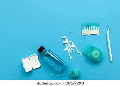 Different tools for dental care on blue background. Toothbrush, cleanser, floss, flossers, wax for braces and interdental brush. Top view. Flat lay. Dental hygiene and care concept