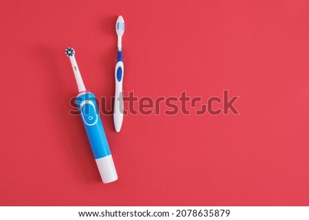 different toothbrushes on red background, electric toothbrush or plastic toothbrush, environmental friendliness lifestyle concept, efficiency of brushing teeth