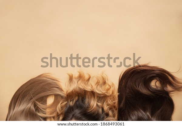 Different type of hair\
blonde, brunette, wavy on beige background, top view. Spa concept\
for root and tip\
care.