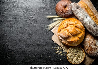 Different types of bread with grain and spikelets. On dark rustic background - Shutterstock ID 1383617072