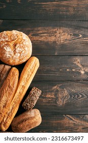 Different types of bread loaves on wooden background with copy space. Bakery, delicious food concept. Top view